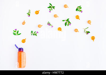 Bottiglia di olio essenziale con prato fresche erbe e fiori su fondo bianco. Appartamento laico, vista dall'alto, naturale Foto Stock