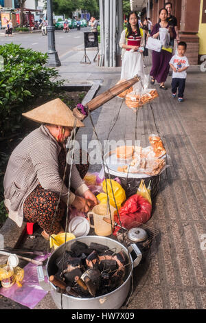 Donna vendita alimentari sulla strada, Ho Chi Minh City, Vietnam Foto Stock