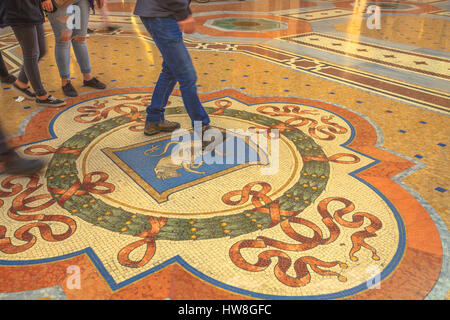 Milano - Marzo 7, 2017: turisti rafforzamento sul Bull di palle di mosaico in Milano all'interno di Galleria Galleria Vittorio Emanuele II in piazza del Duomo. Foto Stock