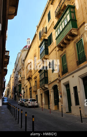 Vista su una tipica strada a La Valletta di Malta, un patrimonio mondiale Unesco città, con ottomano balconi e un cielo blu chiaro Foto Stock