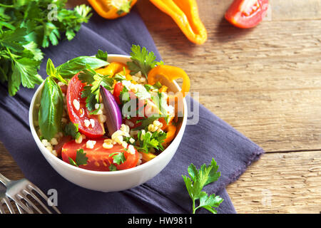 Organico fresco di pomodoro e cuscus insalata di bulgur tabulé con verdure e verdi - vegetariana sana dieta vegana insalata tradizionale in legno rustico Foto Stock