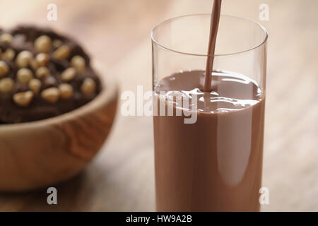 Colata di cioccolato al latte in vetro con cioccolato artigianale biscotti con le nocciole su sfondo Foto Stock