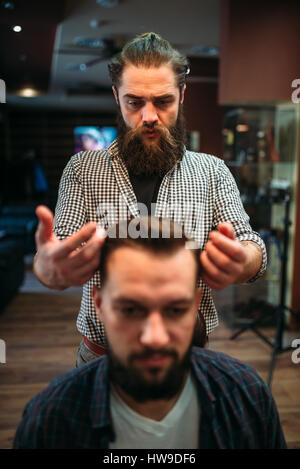 Felice client maschio dopo aver acconciatura presso la Barberia, coiffeur sullo sfondo Foto Stock
