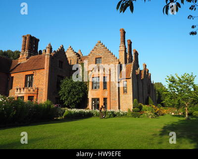 Chenies Manor House che mostra i camini Tudor contro un luminoso cielo blu. Per la cura di prati e alberi tra cui il gelso dal parterre. Foto Stock