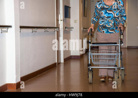 Donna anziana con aiuti a piedi a casa per anziani Foto Stock