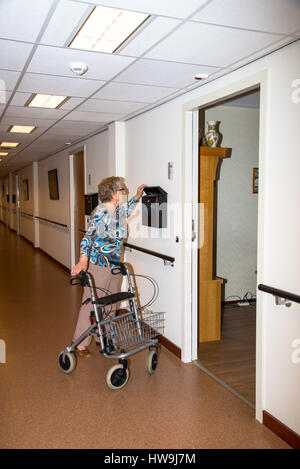 Donna anziana con aiuti a piedi a casa per anziani Foto Stock