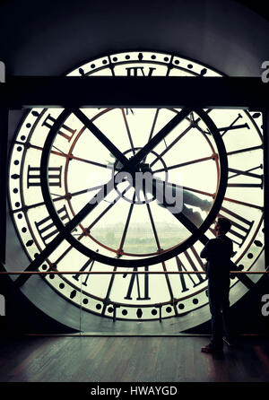 Un turista in cerca thrugh gigantesco orologio torre a Parigi, Francia. Foto Stock