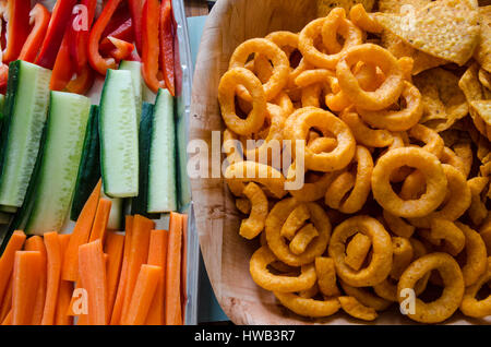Sana e cibo malsano snack scelte con patatine e materie prime vegetali visto bastoni affiancati da sopra. Foto Stock