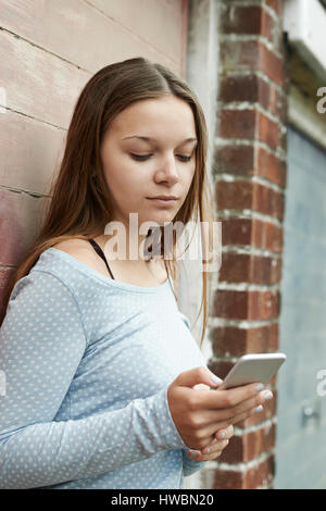 Ragazza adolescente sms sul cellulare nel contesto urbano Foto Stock