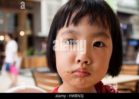 Asian poco ragazza cinese facendo un pasticcio con il cibo in Outdoor Cafe Foto Stock