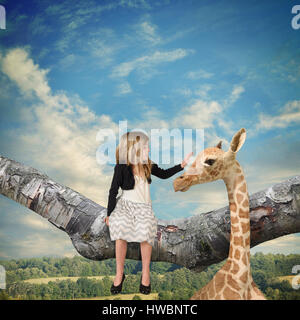 Un bambino piccolo che è seduto su un ramo di albero petting una giraffa fino al cielo per un' immaginazione idea circa gli animali selvatici in Foto Stock