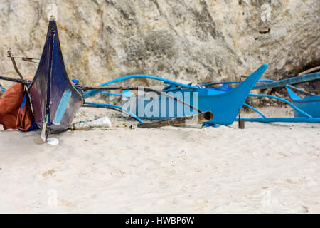 I pescatori filippino della pompa barche fino in bacino di carenaggio sulla spiaggia di sabbia bianca di essere riparato con una pietra calcarea cliff back drop. Foto Stock