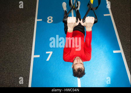 Ricci bianco barbuto uomo sportivo esercitando con cinghie di fitness in palestra Foto Stock