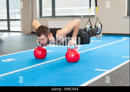 Ricci bianco barbuto uomo sportivo esercitando con cinghie di fitness in palestra Foto Stock