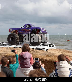 Gli spettatori guardano come Slingshot monster truck schiaccia auto accatastate in sabbia a 2014 Ruote Festival, Bournemouth Dorset Regno Unito Foto Stock