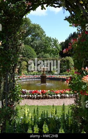 Vista attraverso le frondose archway a graziosamente fiori colorati che confinano con laghetto e fontana alla Corte di Arlington, DEVON REGNO UNITO Foto Stock