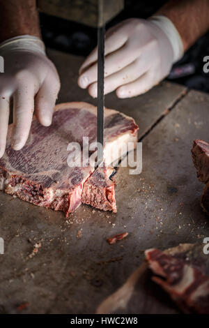 Macellaio è il taglio di carne a fette sulla segatrice a nastro presso lo store Foto Stock