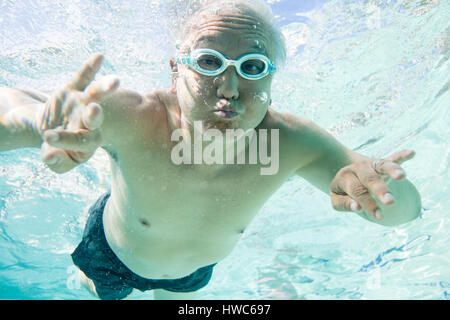 Senior essendo silly sott'acqua in una piscina Foto Stock