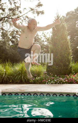 Senior uomo salti in piscina Foto Stock