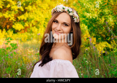 Ritratto di piuttosto attraente bella ragazza sorridente con la corona di fiori di campo estivo Foto Stock