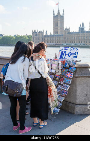 I turisti in Inghilterra. Persone che acquistano le cartoline per la vendita da parte del fiume Tamigi a Londra, Inghilterra, Regno Unito Foto Stock