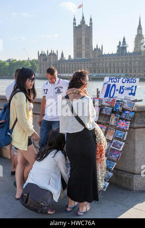 Giovani turisti del Regno Unito. Persone che scelgono le cartoline per la vendita da parte del fiume Tamigi a Londra, Inghilterra, Regno Unito Foto Stock