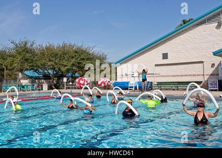 Il gruppo di donne (varie età) frequentando Aerobica, Acqua Gym, istruttore dimostrando, utilizzando styrofoam 'acqua noodles', piscina esterna riscaldata. Foto Stock