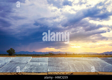 Svuotare tavolo in legno top per display del prodotto montage e campo di riso e il tramonto. Foto Stock