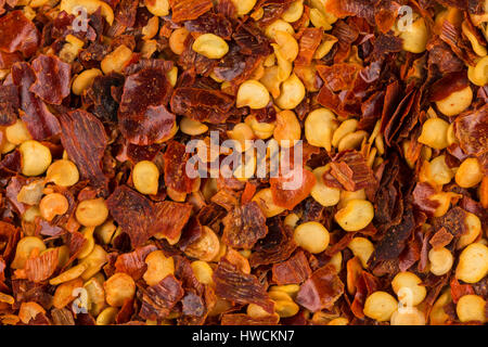 La pila di un peperoncino rosso tritato, peperoncino essiccato in scaglie e semi come sfondo Foto Stock