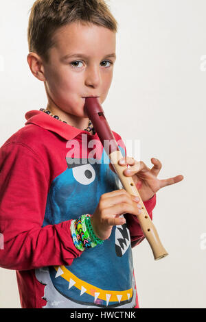 Un bambino gioca su un flauto di legno. Educazione musicale e scuola di musica., Ein tipo spielt auf einer Flöte auf Holz. Musikerziehung und Musikschule. Foto Stock
