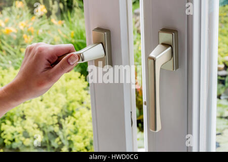 Una donna si apre una finestra per i venti del piatto. Aria fresca in camera, Eine Frau ˆffnet ein Fenster zum L'ften der Wohnung. Frische Luft im Zimmer Foto Stock