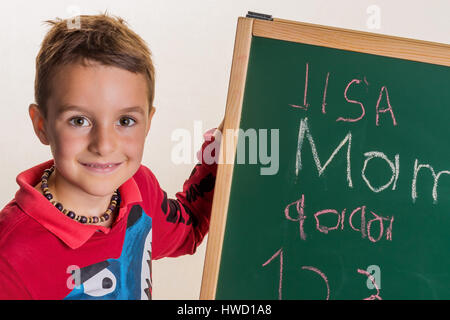 " Un Bambino scrive la parola "false" su un bordo della scuola", ein tipo schreibt das Wort ' Mama ' auf eine Schultafel Foto Stock