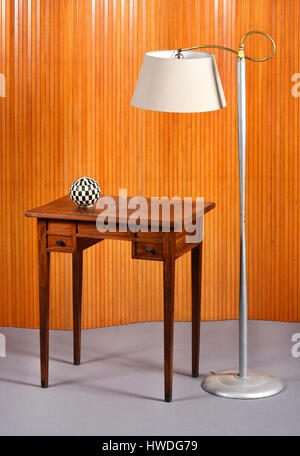 Mobili di vita ancora di metallo Lampada da terra con paralume appeso accanto a Piccola scrivania in legno con in bianco e nero a scacchi globo decorativo in camera con il grigio Foto Stock