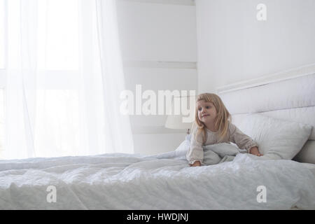 Little Baby girl è di alzarsi al mattino con il sorriso, concetto bianco Foto Stock