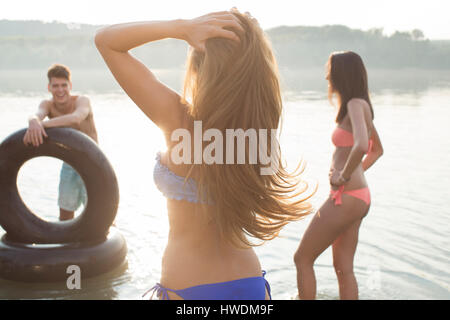 Gli amici si divertono con anello gonfiabile in fiume Foto Stock