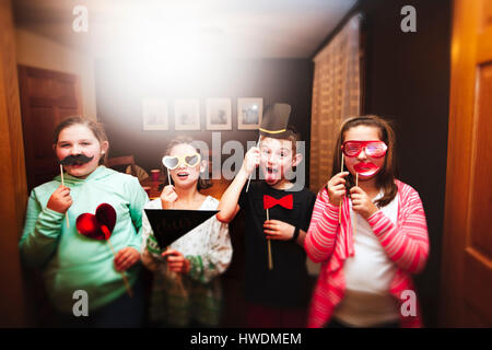 Ritratto di un ragazzo e tre ragazze tenendo gli occhiali da sole e baffi stick maschere a parte Foto Stock