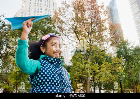 Ragazza gettando aeroplano di carta sorridente, New York, Stati Uniti d'America Foto Stock