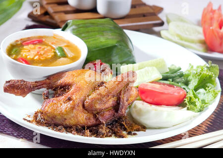 Ayam goreng pollo fritto cibo Indonesia, servire con piatto di tamarindo, sayur asam e riso Foto Stock