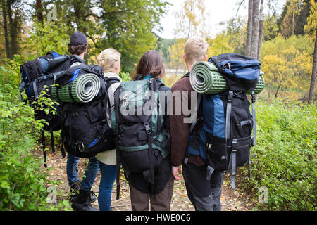 Amici con zaini e tappetini di laminati in foresta Foto Stock