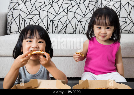 Asian poco ragazze cinesi di mangiare la pizza a casa Foto Stock