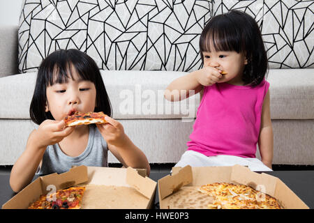 Asian poco ragazze cinesi di mangiare la pizza a casa Foto Stock