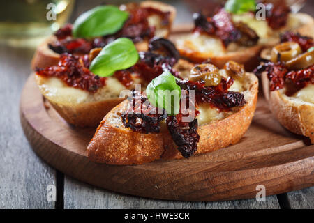 Antipasto bruschetta con pomodori secchi e olive e mozzarella. Cucina italiana Foto Stock