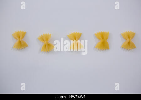 Farfalle di pasta disposte in una fila su sfondo bianco Foto Stock