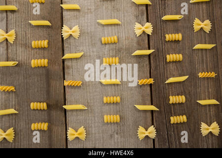 Varie pasta disposte in fila su una superficie di legno Foto Stock