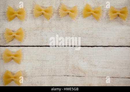 Farfalle di pasta disposte in una fila sullo sfondo di legno Foto Stock