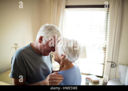 Coppia senior romancing in camera da letto a casa Foto Stock