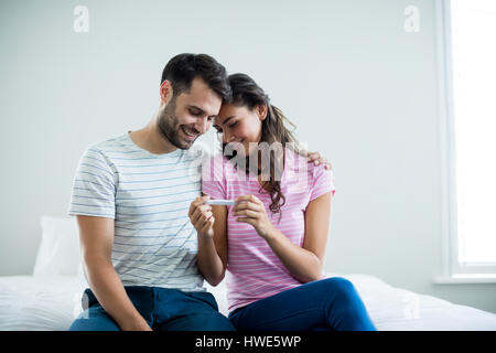 Gioiosa giovane trovare i risultati di un test di gravidanza in camera da letto a casa Foto Stock