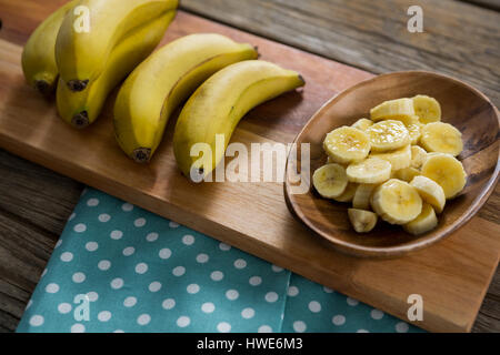 Sovraccarico di banana e fette di banana in piastra tenuta sul tagliere Foto Stock