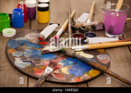 Tavolozza di colori multipli, acquarello e pennelli per dipingere su tavola in legno Foto Stock