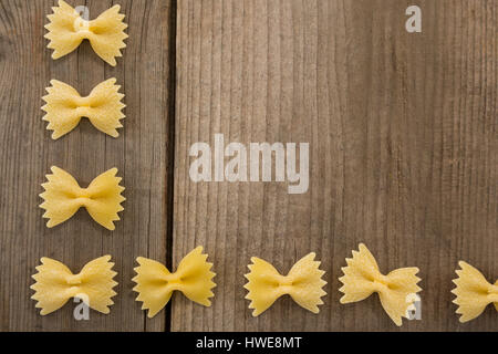 Farfalle di pasta disposte in fila su una superficie di legno Foto Stock